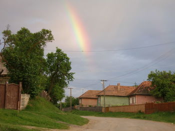 Rainbow over houses against cloudy sky