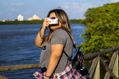 Young woman photographing on mobile phone in water