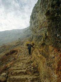 Low angle view of man climbing on rocky mountains against sky