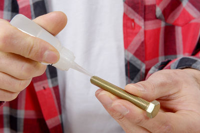 Midsection of worker applying glue on screw