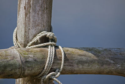 Close-up of rope tied on wooden post against sky