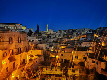 Illuminated buildings in city against clear blue sky