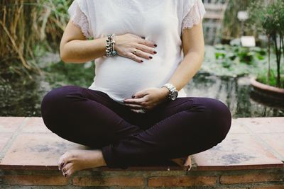 Midsection of woman wearing hat sitting outdoors