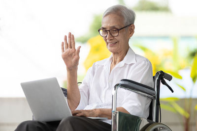 Senior woman waving during video call on laptop