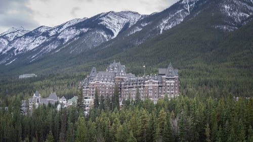 Luxury castlelike mountain hotel in a forest under the mountains, wide shot, banff, canada