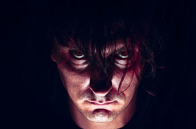 Close-up portrait of young man against black background