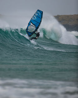 Person paragliding in sea against sky