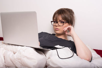 Woman using laptop on bed at home