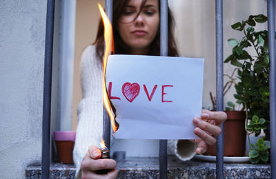 Close-up of woman holding hands while standing against wall