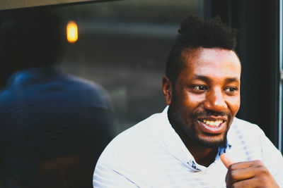 Happy young man looking away while sitting by window