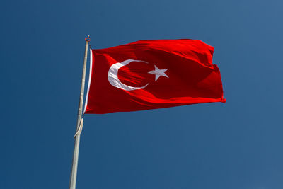 Low angle view of flag against blue sky