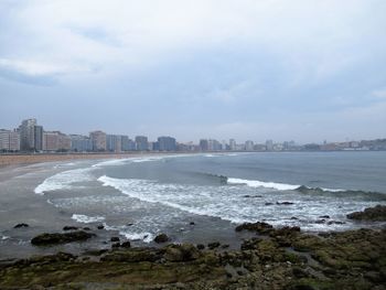 Scenic view of sea by buildings against sky