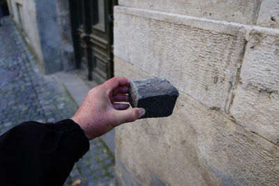 Close-up of man holding cigarette against brick wall
