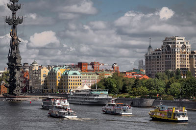 Ferry boats by peter the great statue in moskva river against cloudy sky