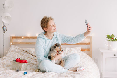Woman taking selfie picture with cute puppy dog pet on smartphone. distant holiday celebration 