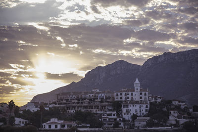 Houses in town against cloudy sky