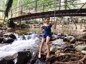 Full length portrait of sitting on swing over river