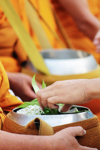 Midsection of man holding orange while standing at temple