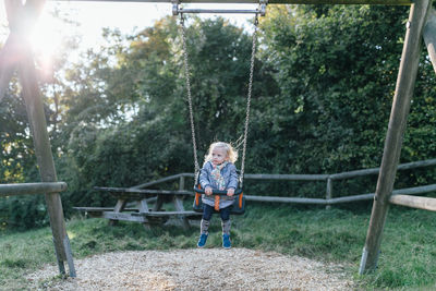 Full length of cute girl swinging at playground