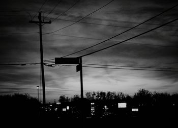 Low angle view of electricity pylon against cloudy sky