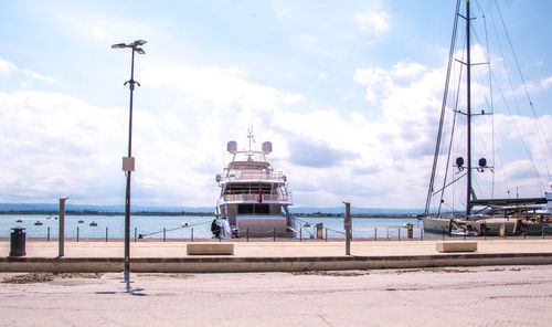 Sailboats moored at harbor against sky