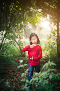 Portrait of girl making face while standing in forest