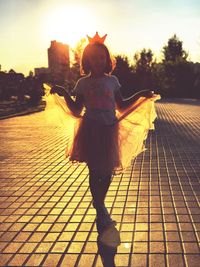 Rear view of woman standing against sky during sunset