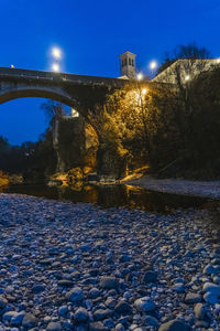 Illuminated bridge over river against sky