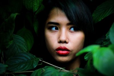 Close-up of serious young woman amidst leaves