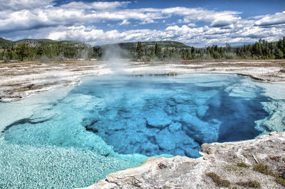 Scenic view of geyser and mountain against sky