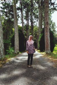 Full length of woman standing on road in forest