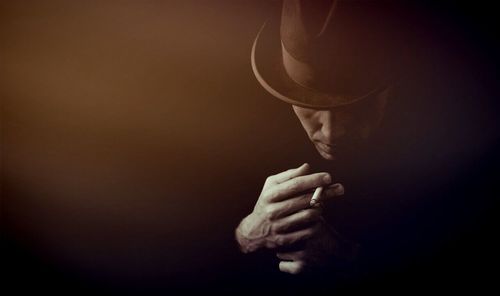 Man smoking cigarette against colored background