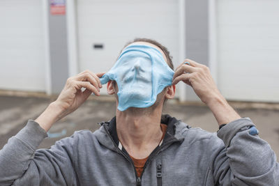 Close-up of man putting mask on face outdoors