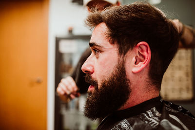 Cropped hands of barber grooming customer in salon