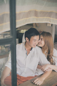 Smiling couple sitting at table seen through window