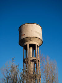 Low angle view of water tower against clear blue sky