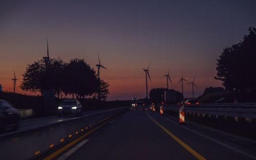Cars on road against sky at sunset