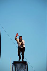 Low angle view of woman standing against clear blue sky