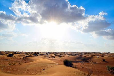 Scenic view of desert against cloudy sky