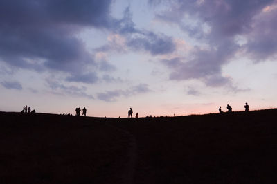 Silhouette people on field against sky during sunset