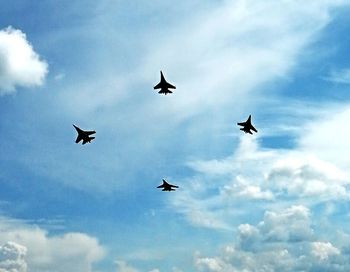 Low angle view of airplane flying against cloudy sky