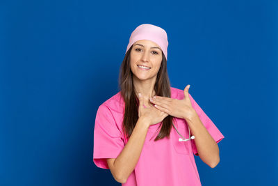 Portrait of smiling young woman standing against blue sky