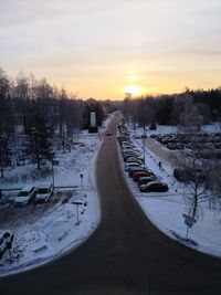 Snow covered field against sky during sunset