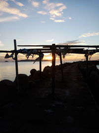 Silhouette pier on beach against sky during sunset