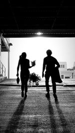 Silhouette man walking on street against sky