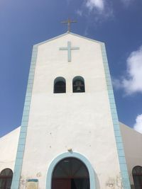 Low angle view of cross and building against sky