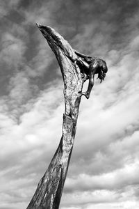Low angle view of statue on dead tree against sky