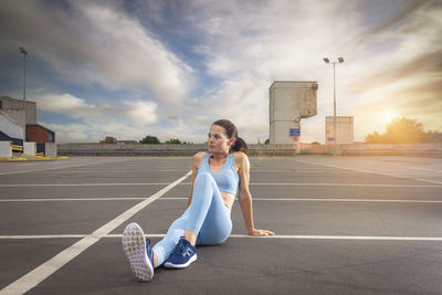 Sporty woman sitting and relaxing after exercise, urban background