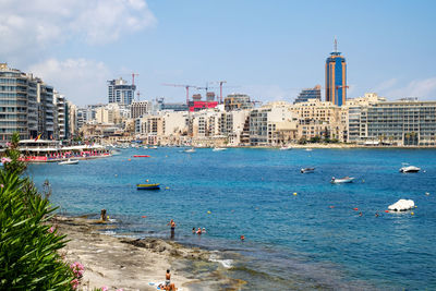 Boats in sea against buildings in city