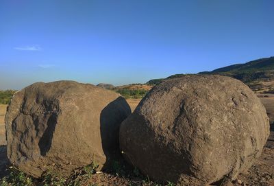 Scenic view of rocks on field against blue sky